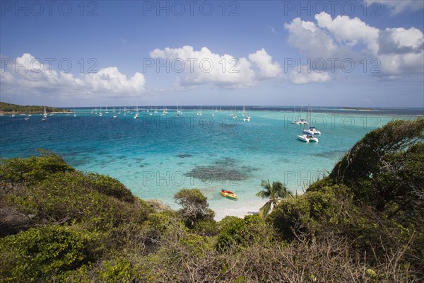 WEST INDIES, St Vincent & The Grenadines, Tobago Cays, View across the beach at Jamesby Island towards moored yachts