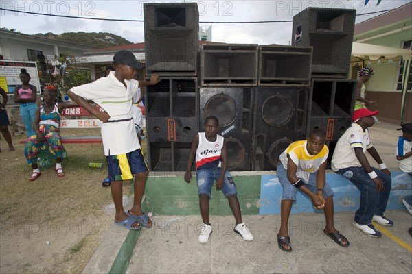 WEST INDIES, St Vincent & The Grenadines, Union Island, Young men sitting beneath a sound system at the Easterval Easter Carnival in Clifton