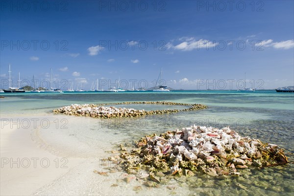 WEST INDIES, St Vincent & The Grenadines, Union Island, Conch shell structures on the beach at Clifton Harbour with yachts moored behind