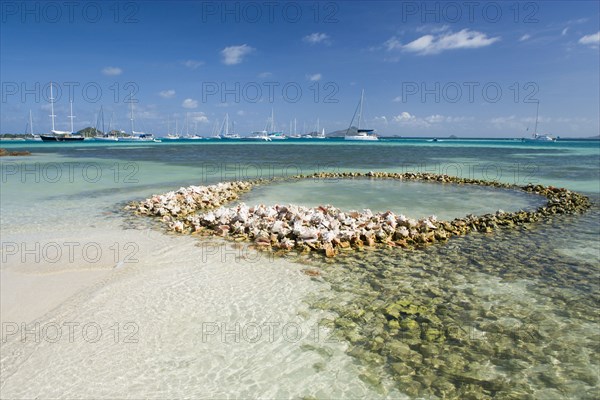 WEST INDIES, St Vincent & The Grenadines, Union Island, Conch shell structures on the beach at Clifton Harbour with yachts moored behind
