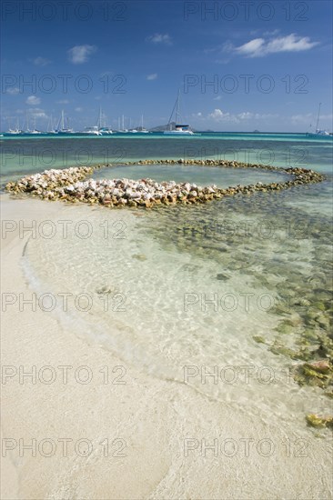 WEST INDIES, St Vincent & The Grenadines, Union Island, Conch shell structures on the beach at Clifton Harbour with yachts moored behind