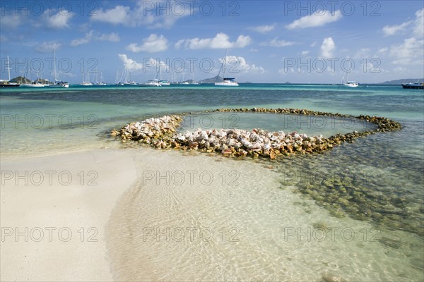 WEST INDIES, St Vincent & The Grenadines, Union Island, Conch shell structures on the beach at Clifton Harbour with yachts moored behind