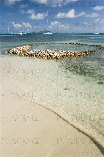 WEST INDIES, St Vincent & The Grenadines, Union Island, Conch shell structures on the beach at Clifton Harbour with yachts moored behind