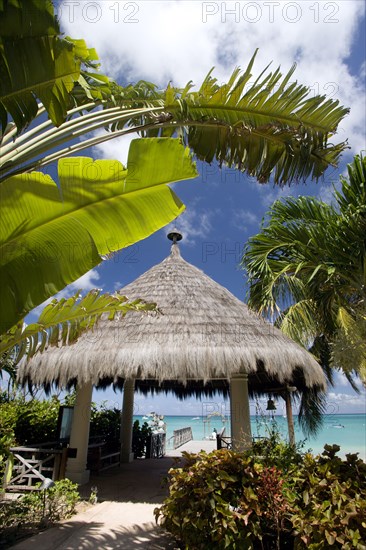 WEST INDIES, St Vincent & The Grenadines, Canouan, Palapa thatched entrance from hotel jetty at Tamarind Beach Hotel in Charles Bay