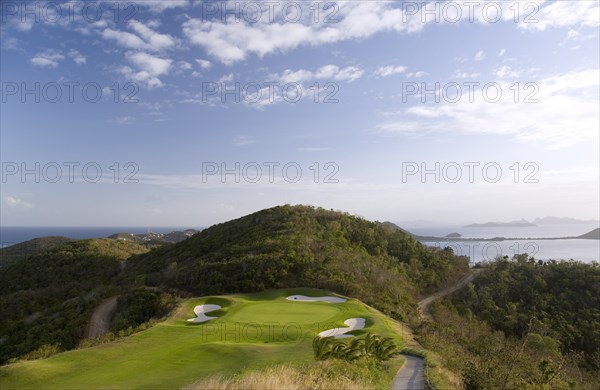 WEST INDIES, St Vincent & The Grenadines, Canouan, Raffles Resort showing the 12th green on the Trump International Golf course with the southern Grenadine islands in the distance