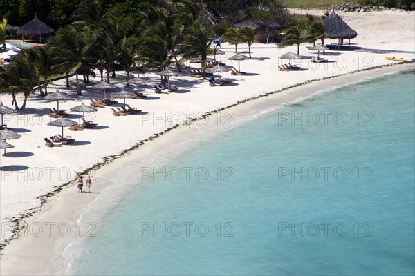 WEST INDIES, St Vincent & The Grenadines, Canouan, Two women walking along Jambu Beach at Raffles Resort