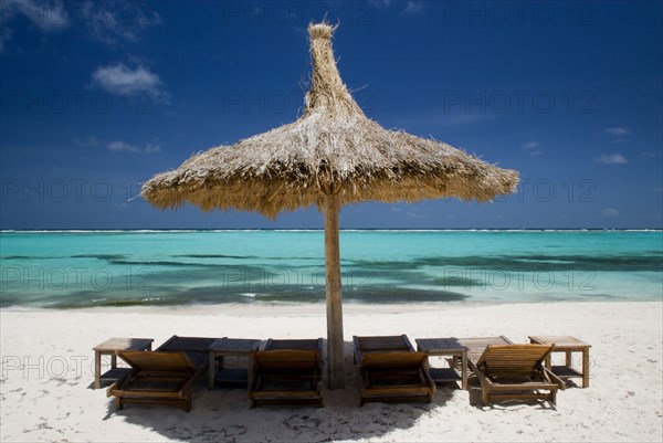 WEST INDIES, St Vincent & The Grenadines, Canouan, Palapa thatched shelter and sunbeds on Godahl Beach at Raffles Resort