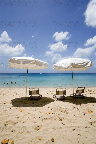 WEST INDIES, Barbados, St Peter, Sun shade umbrellas and chairs on Gibbes Beach with people swimming in the calm sea