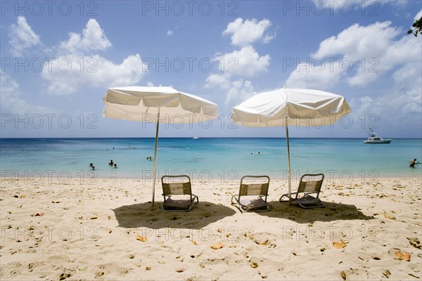 WEST INDIES, Barbados, St Peter, Sun shade umbrellas and chairs on Gibbes Beach with people swimming in the calm sea