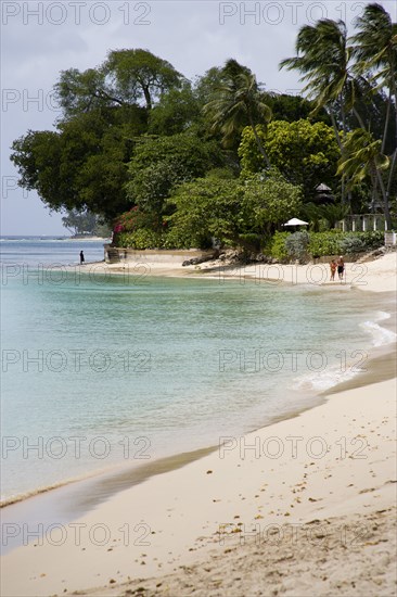 WEST INDIES, Barbados, St Peter, People walking along beach at Gibbes Bay past one of the exclusive houses
