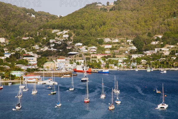 WEST INDIES, St Vincent & The Grenadines, Bequia, Port Elizabeth with yachts moored in Admiralty Bay with the ferry port and hillside housing beyond
