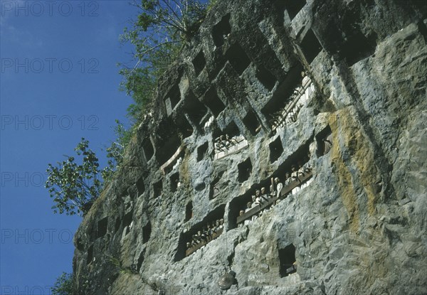 INDONESIA, Sulawesi, Toraja wooden funeral effgies or tau tau set into cliff outside the family tomb or liang torepresent the spirit of the deceased.