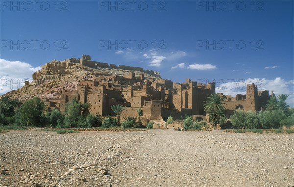 MOROCCO, Ait Benhaddou, Kasbah famous for appearing in films such as Jesus of Nazareth and Lawrence of Arabia.  Exterior walls with small group of people in foreground.