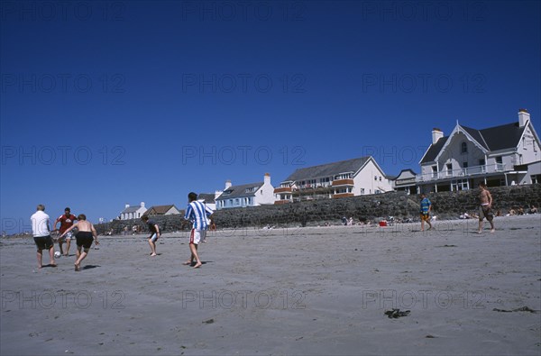 UNITED KINGDOM, Channel Islands, Guernsey, Castel. Cobo Bay. Young men playing football on sandy beach