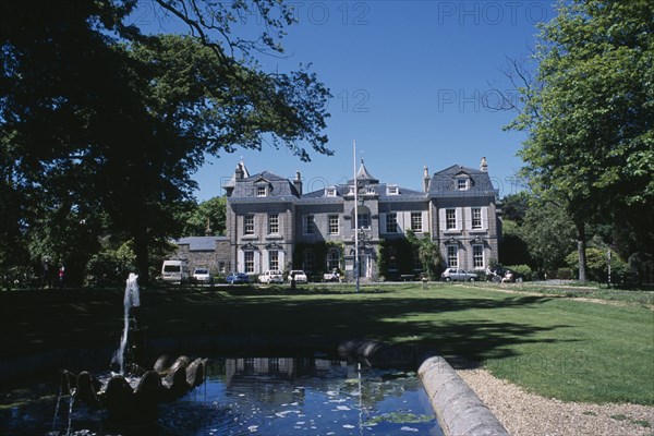 UNITED KINGDOM, Channel Islands, Guernsey, St Martins. Saumarez House. View of front entrance from green lawn over pond.