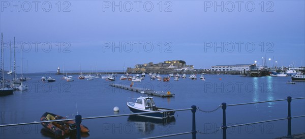 UNITED KINGDOM, Channel Islands, Guernsey, St Peter Port. Cornet Castle at dusk seen from across water.