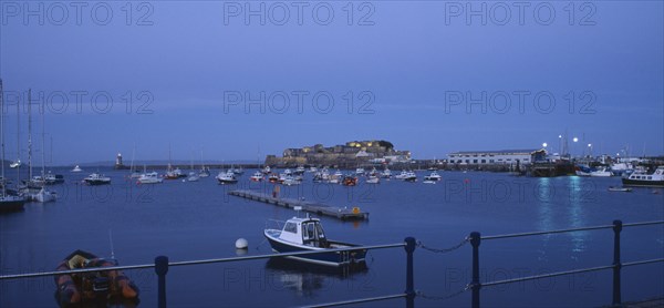 UNITED KINGDOM, Channel Islands, Guernsey, St Peter Port. Cornet Castle at dusk seen from across water.