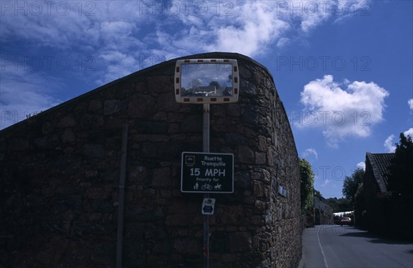 UNITED KINGDOM, Channel Islands, Guernsey, St Saviours. Convex mirror on stone wall with reflection of a small white cottage