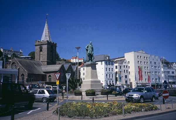 UNITED KINGDOM, Channel Islands, Guernsey, "St Peter Port. Albert Prince Consort statue on weighbridge roundabout with the town church behind. The Albion House pub, restaurants, and shops lining the esplanade"