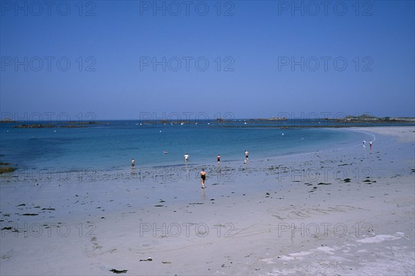 UNITED KINGDOM, Channel Islands, Guernsey, Castel. Cobo Bay. Sandy beach with people paddling at the waters edge