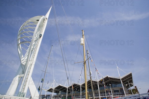 ENGLAND, Hampshire, Portsmouth, The Spinnaker Tower the tallest public viewing platforn in the UK at 170 metres on Gunwharf Quay with yachts mast in the foreground and waterfront attractions behind