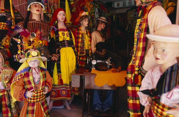 BOLIVIA, La Paz, "Costume maker for Oruro Carnival. Man working on sewing machine, surrounded by mannequins."