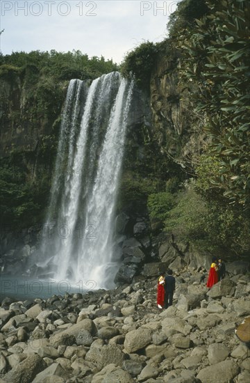 SOUTH KOREA, Cheju Island, Honeymoon Falls, Couples in traditional dress at rocky foot of waterfall.