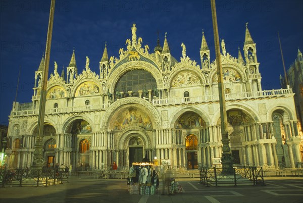 ITALY, Veneto, Venice, Basilica di San Marco exterior facade at night with clothing stall in square in the foreground