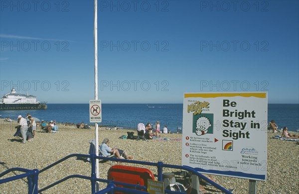 ENGLAND, East Sussex, Eastbourne, Child safety awarness sign Kid Zone displayed next to railings on busy beach.