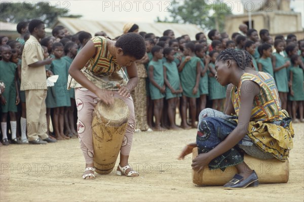 CONGO, Tribal People, African women drummers with group of schoolchildren listening behind.