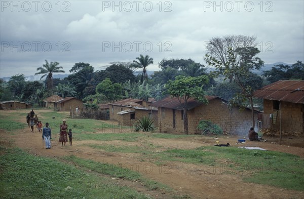 ANGOLA, Vige, Mud brick village houses with people on unmade road outside.