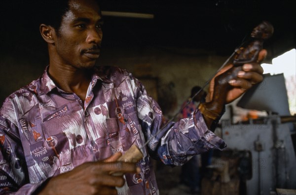 RWANDA, Gisenyi, Wood carver at Kiaka Artisans Co-operative producing goods for export and local consumption in area that has seen genocide and the passage of one million refugees.