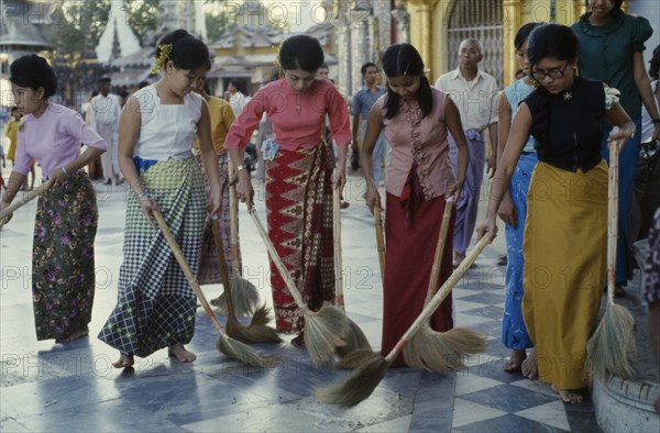 MYANMAR, Yangon, Schwedagon Pagoda.  Women sweeping black and white chequered floor of pagoda.