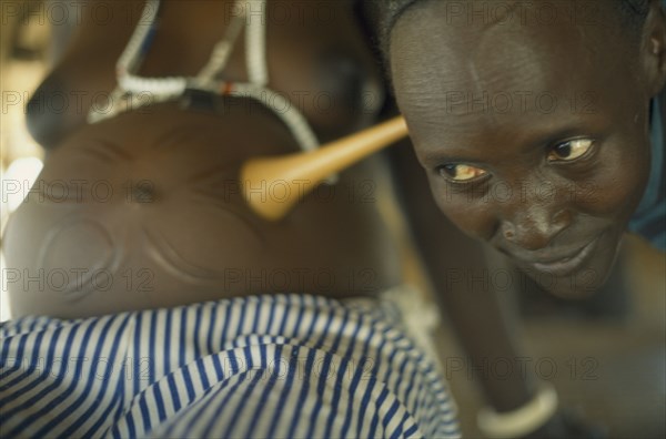 SUDAN, Bahr el Ghazal, Traditional midwife Josephine listening to foetal heart during examination of patient.