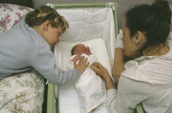 CHILDREN, Relationships, Siblings, Mother and five year old son looking at week old sister lying in cot.