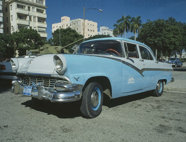 CUBA, Havana, A blue and white taxi parked ouside the Museo de la Revolution with a tank behind.