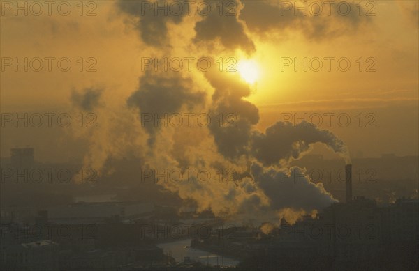RUSSIA, Moscow, Setting sun partly obscured by plume of thick smoke from industrial chimney.