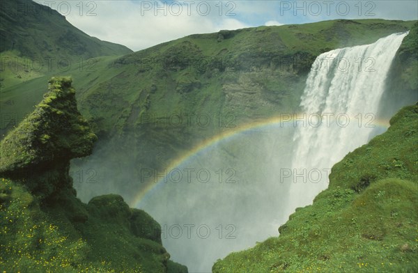ICELAND, Skogarfoss, Rainbow over plunging waterfall from the south coast road.