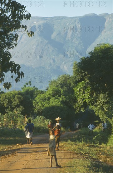 MALAWI, Mulanje, People walking along path in area of tea growing and subsistence farming with Mount Mulanje in the distance.