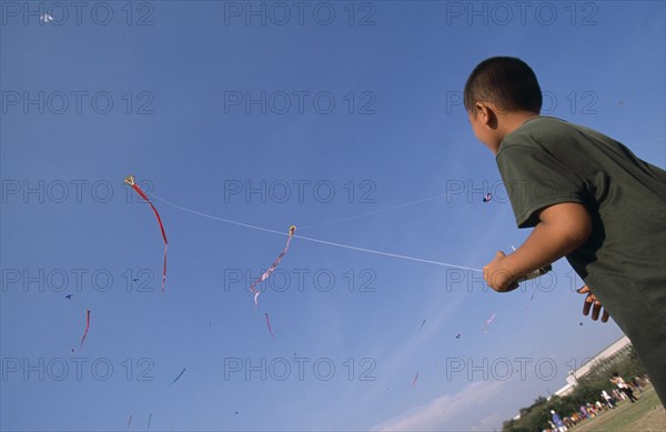 THAILAND, Bangkok, "Kite festival at Sanam Luang, February. Boy flying one in foreground, many others in sky."