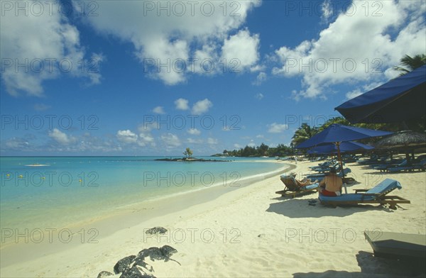 MAURITIUS, Grand Bay, The beach at the Mauritius Hotel. People on sun loungers  and umbrellas.