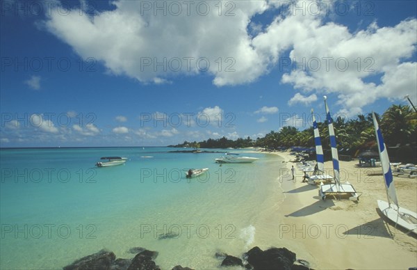 MAURITIUS, Grand Bay, The beach at the Mauritius Hotel. People next to yachts with blue and white sails.