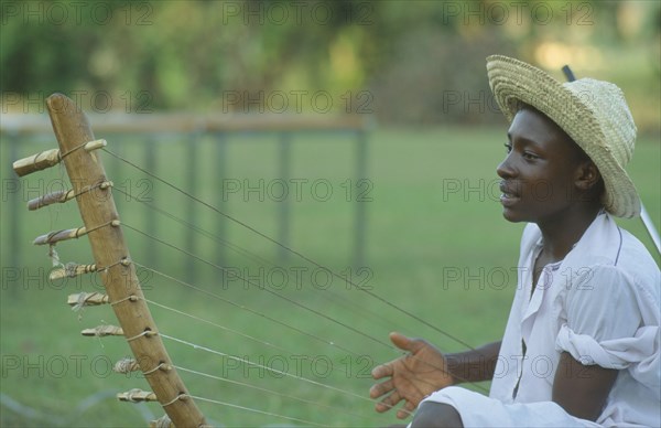 UGANDA, Kampala, Folk musician playing harp like instrument.