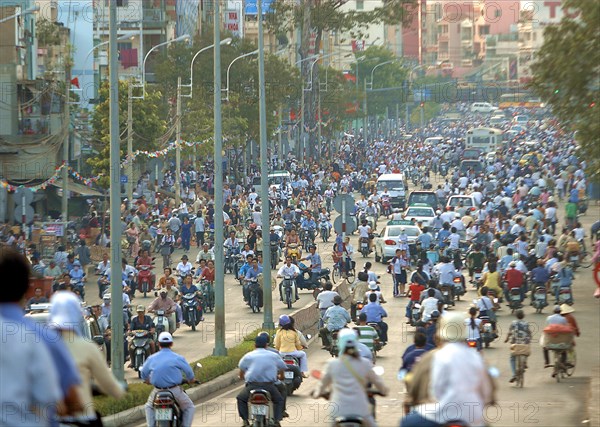 VIETNAM, South, Ho Chi Minh City, View down busy street with people riding motorbikes and bicycles