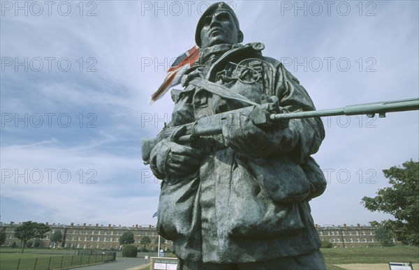ENGLAND, Hampshire, Portsmouth, Royal Marines Museum. Large statue of a Royal Marine holding a gun displayed at Main entrance with a Union Jack flag fyling behind.