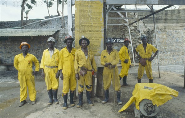 ZIMBABWE, Industry, Group of miners in safety helmets and work clothes at Patchway gold mine with Code of Signals mining regulations notice behind them.