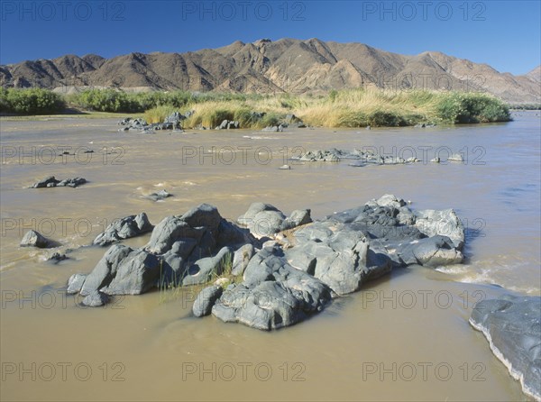 NAMIBIA, South, Orange River, Rocks in the  water in The Orange River further west after being joined by the Fish River.