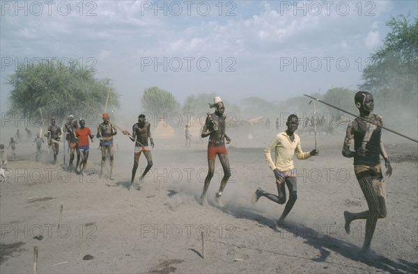 SUDAN, People, Young Dinka men carrying spears and running in line.