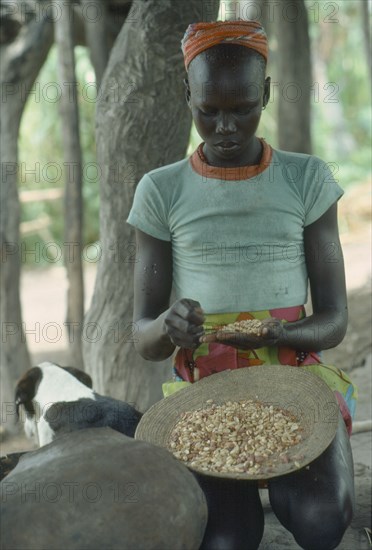 SUDAN, People, Dinka tribeswoman shelling groundnuts.