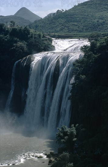 CHINA, Guizhou Province, Huangguoshu Falls, Waterfall cascading from vegetation covered karst cliffs.